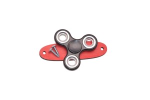 Czarny spinner do tablicy sensorycznej na czerwonej podstawce.  