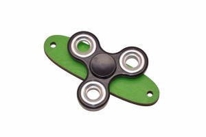 Czarny spinner do tablicy sensorycznej na zielonej podstawce. 