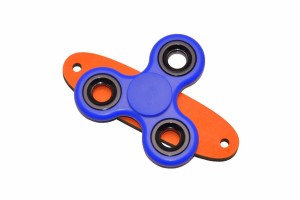 Granatowy spinner do tablicy sensorycznej na pomarańczowej podstawce.    
