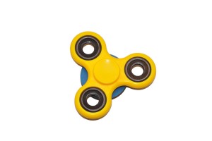 Żółty spinner na podstawce niebieskiej na tablicę manipulacyjną.  